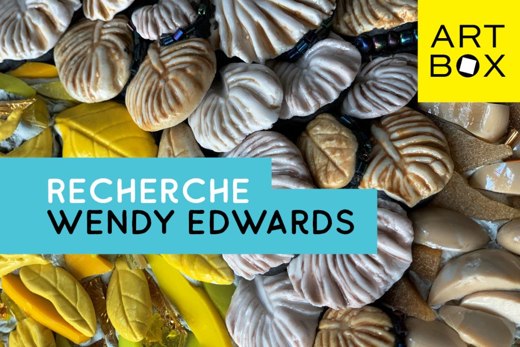 Close-up of an intricate art piece featuring textured shells and beads. The composition includes cream and brown shell-like elements with black beads and yellow leaves. Overlaid text reads RECHERCHE WENDY EDWARDS beside a yellow ART BOX logo.