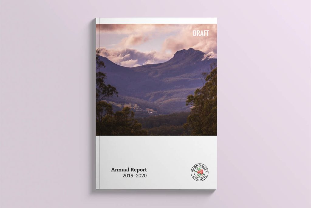 Cover of an annual report draft for 2019–2020 featuring a scenic mountain landscape with green hills and cloudy skies. A logo is at the bottom right.