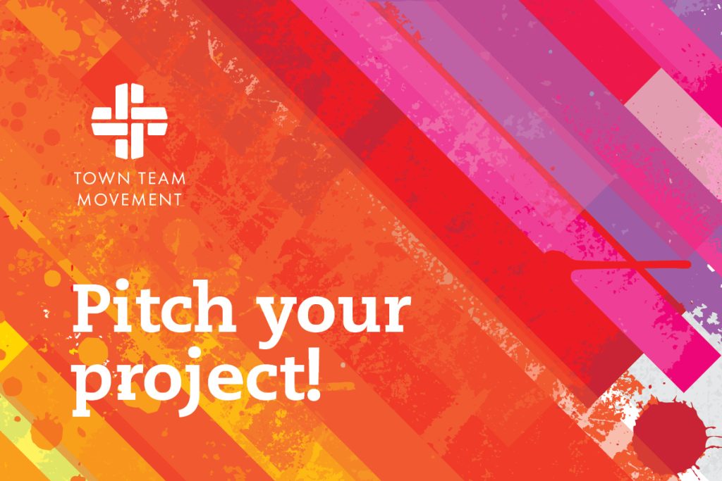 Colorful abstract design with overlapping diagonal stripes in shades of red, orange, and purple. White text reads Pitch your project! and the top left features a logo with a cross pattern and the words Town Team Movement.