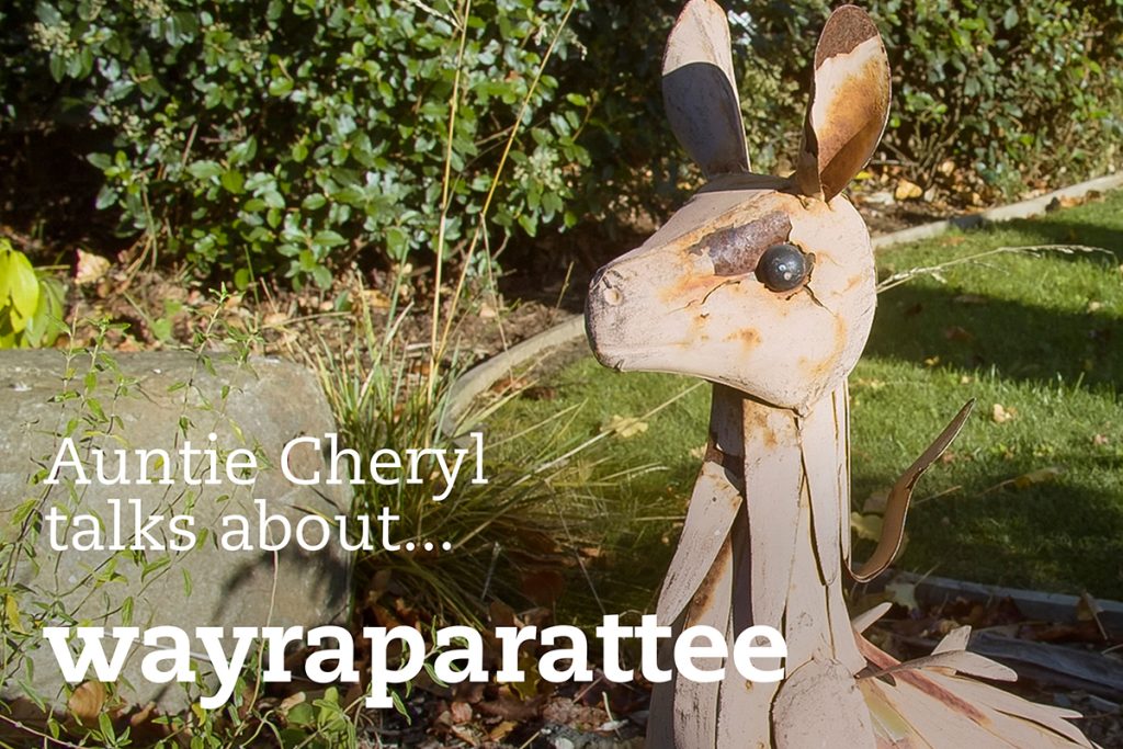 A garden scene featuring a whimsical metal sculpture of a kangaroo. The sculpture is surrounded by greenery. Text on the image reads, Auntie Cheryl talks about... wayraparatee.