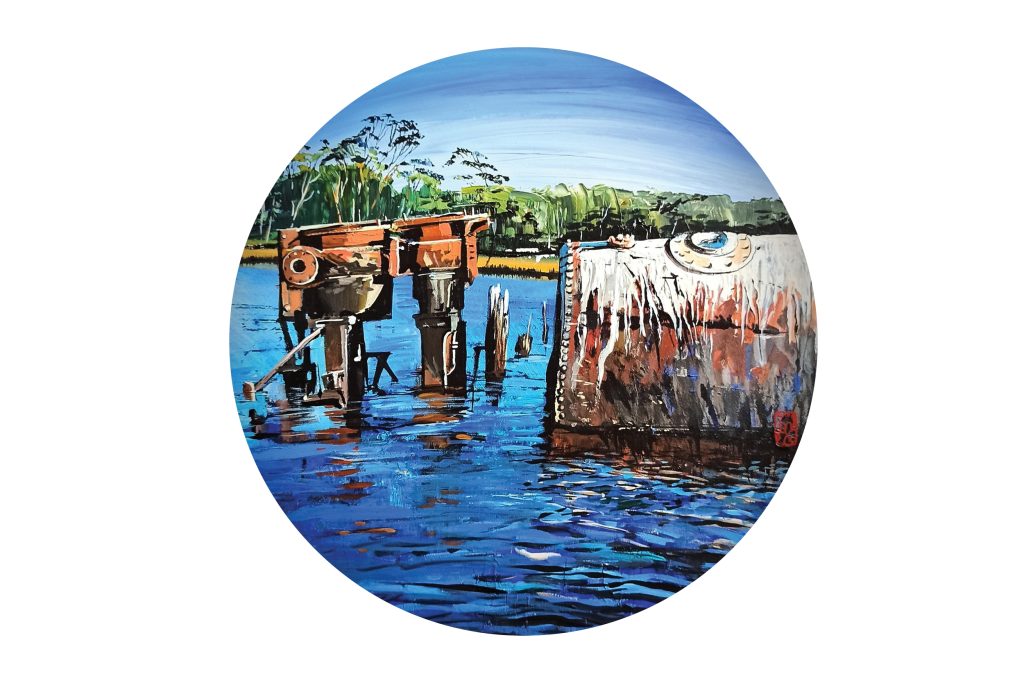A circular painting of a water scene with rusty industrial structures partially submerged. Lush greenery is visible in the background under a clear blue sky, reflecting in the water.