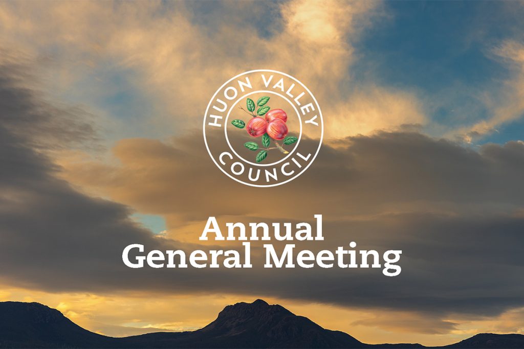 Logo of the Huon Valley Council featuring an apple and leaves on a cloudy sky background. Text reads Annual General Meeting with mountains silhouetted at the bottom.