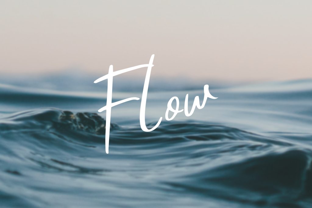 The image shows the word Flow written in elegant, cursive white text over a background of gentle ocean waves, capturing a serene and calm atmosphere with soft lighting.