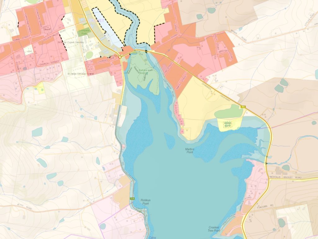 A detailed map displaying a lake surrounded by various colored areas indicating different regions or zones. Roads and paths are marked in yellow and orange, with contour lines showing elevation. Dotted lines highlight specific boundaries around the north.