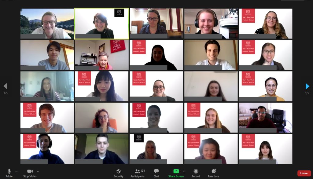 A Zoom video call with 25 participants in a grid layout. Each persons video is turned on, and many have a red and white logo in their background. The interface displays usual meeting controls at the bottom.