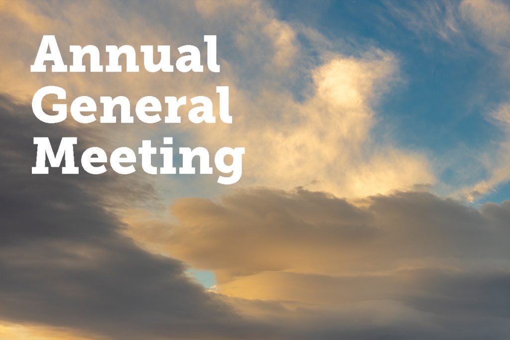 Cloud-filled sky with soft golden and blue hues. The words Annual General Meeting are prominently displayed in white text on the left side.