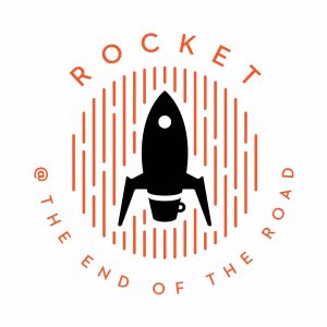 A black rocket silhouette over a small coffee cup, surrounded by orange vertical lines. Circular orange text reads ROCKET @ THE END OF THE ROAD around the design on a white background.