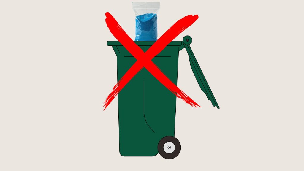 A green trash bin with a bag of blue material inside is shown with a large red X over it, indicating not to throw the bag in the bin.
