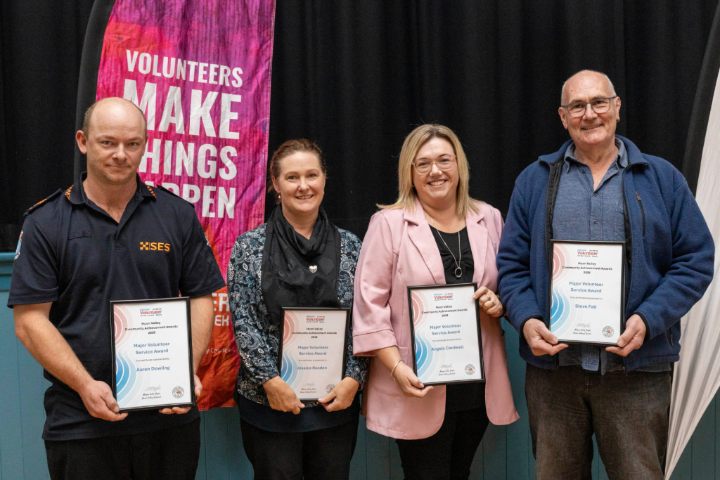 Four volunteers smile as they hold up awards at an event. From left to right: Aaron Dowling, Jessica Readon, Angela Cordwell, and Steve Fall.