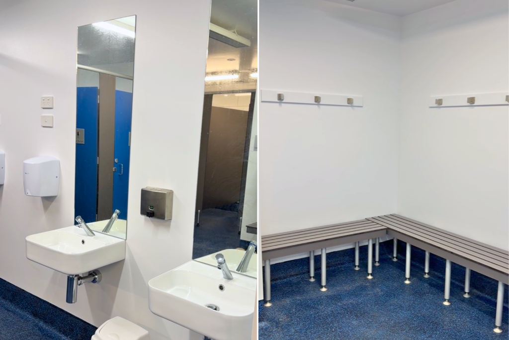 Split image of a locker room: left side shows two sinks with soap and paper towel dispensers under a mirror; right side shows white benches and wall hooks against plain white walls and blue flooring.