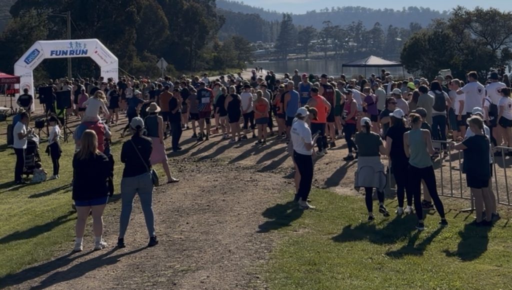 A large group of people gathers at the starting line of a Fun Run event.