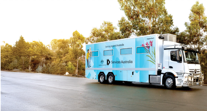 A white Services Australia mobile service truck parked on a road beside a line of trees.